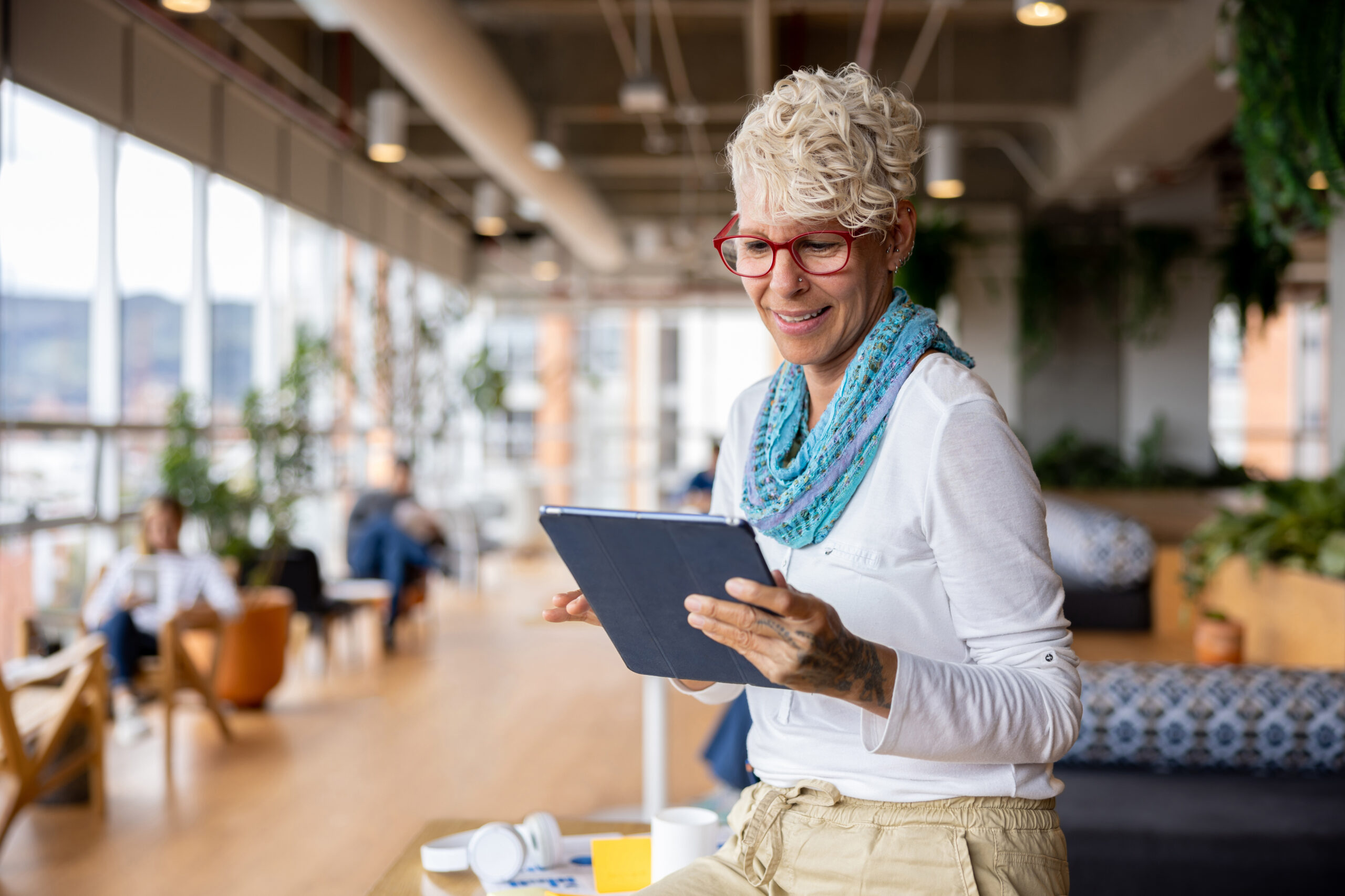 Woman looking at tablet in office setting.