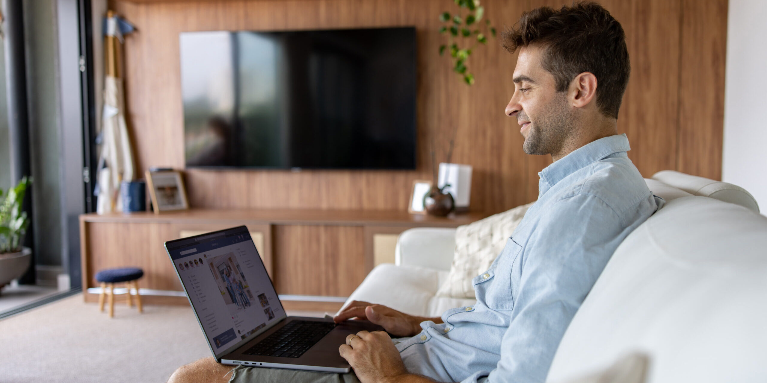 Brazilian man at home using his laptop and looking at social media