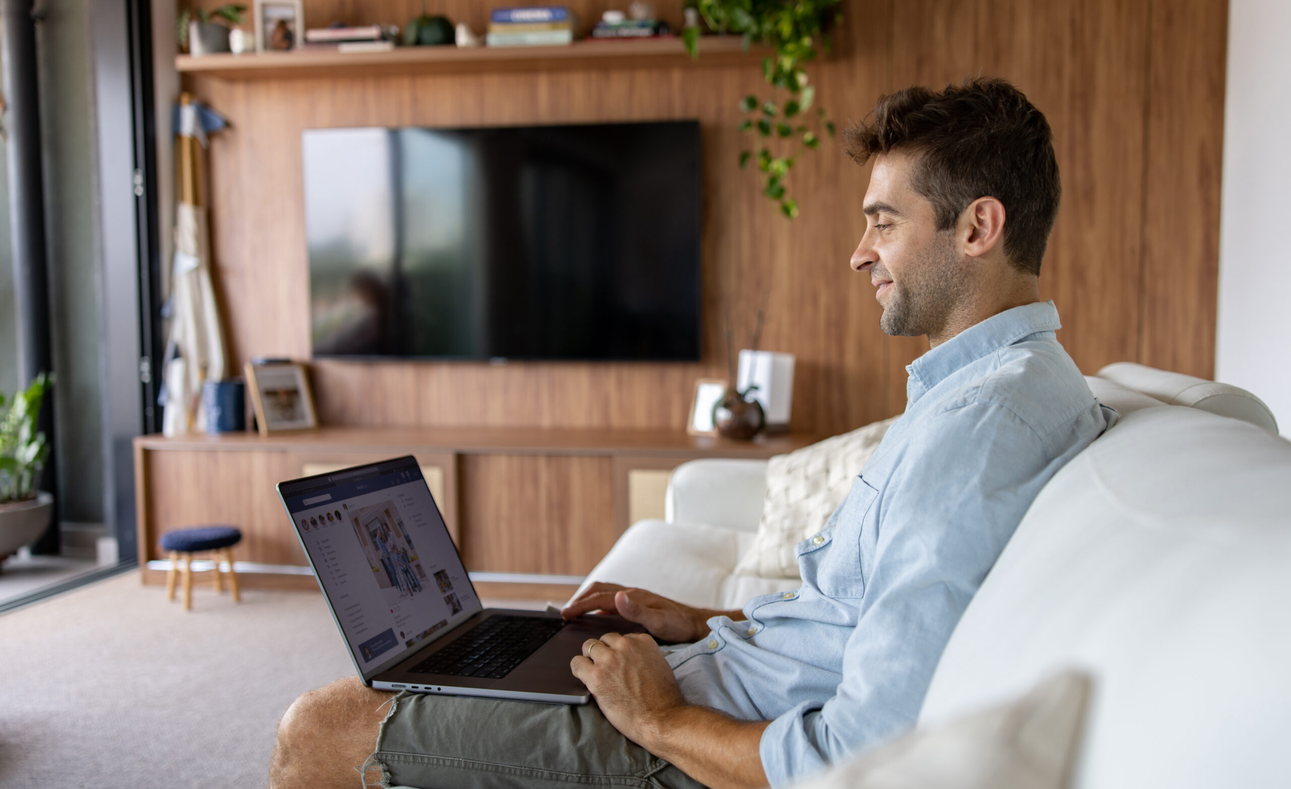 Brazilian man at home using his laptop and looking at social media
